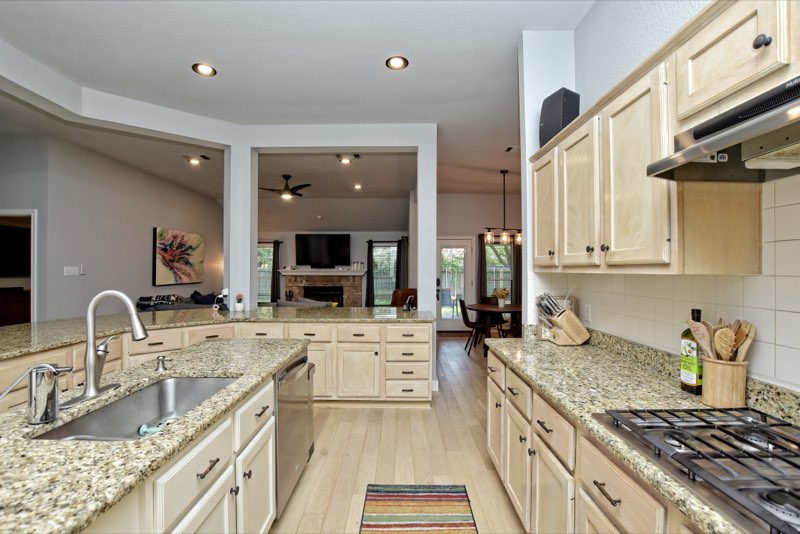 Galley-style kitchen with granite counters, maple cabinets and a view into the family room