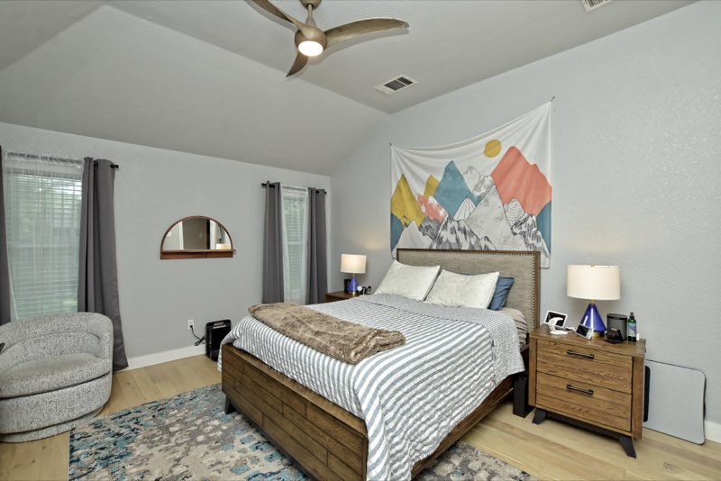 Spacious primary bedroom with vaulted ceiling, ceiling fan and multiple windows